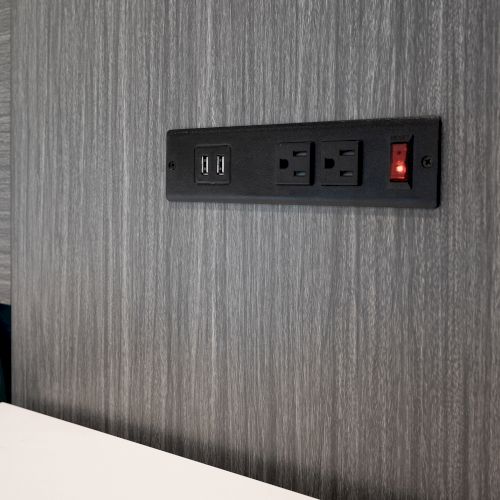 A wall outlet with two USB ports, two electrical sockets, and a switch with a red indicator light on a gray textured background.