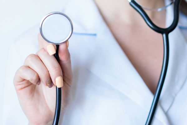 A person in a white coat is holding a stethoscope, suggesting a medical professional.