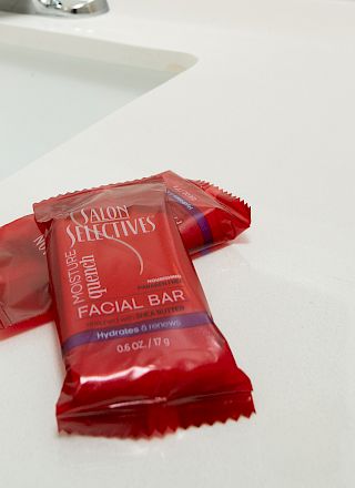 Two red wrapped facial bars are placed on a white countertop beside a sink.